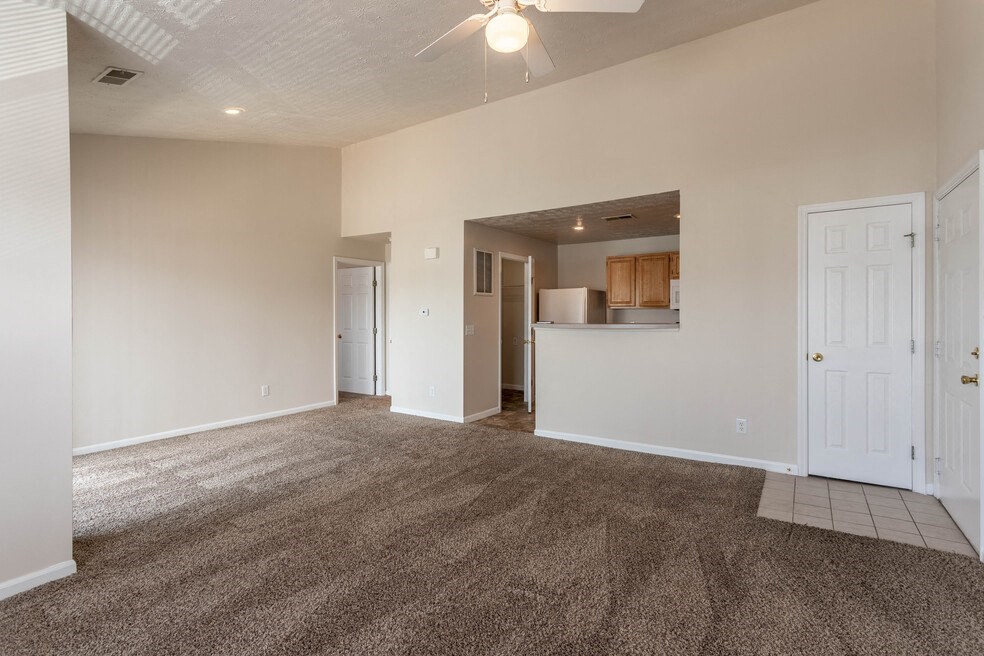 an empty living room with carpet and a kitchen