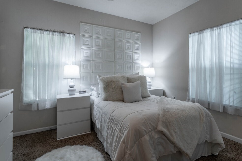 a bedroom with a bed and two windows