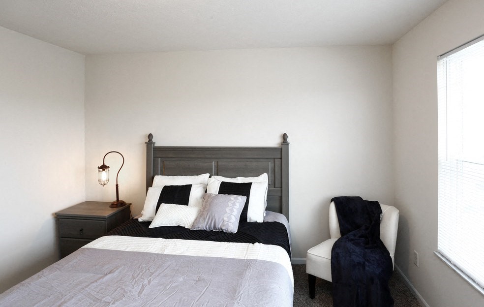 a bedroom with a bed and a chair and a window