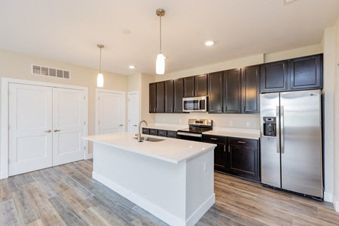 a white kitchen with black cabinets and stainless steel appliances