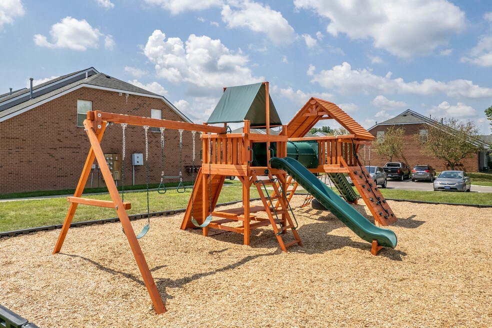a swing set with a green slide in a backyard