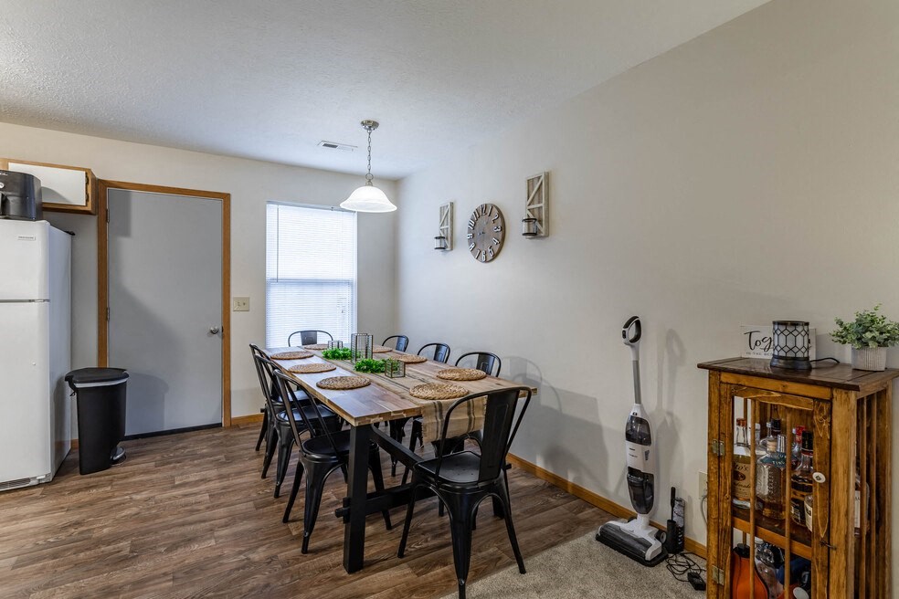 the dining room has a large table and chairs and a refrigerator