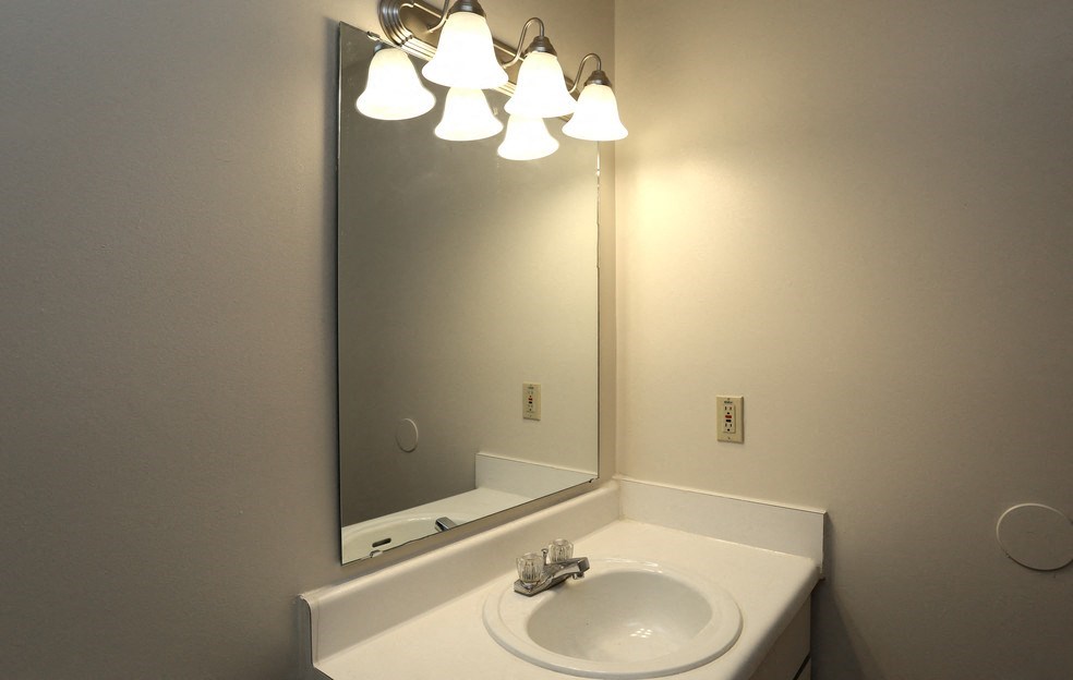 a bathroom with a sink and a mirror with lights above it
