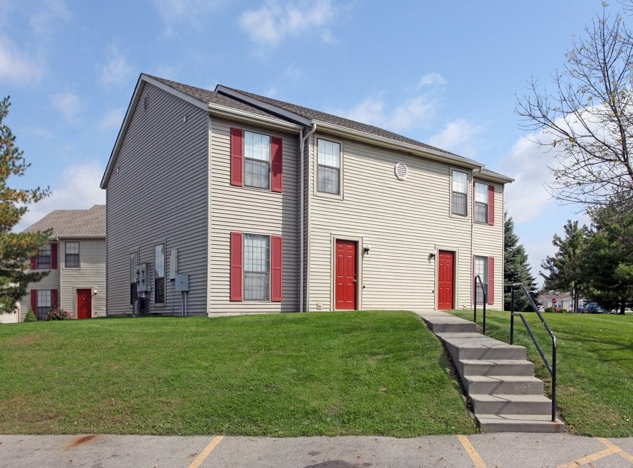 a yellow house with red doors on a green lawn