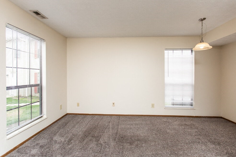 an empty living room with large windows and carpet