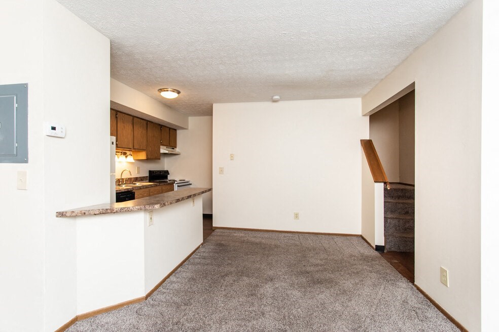 an empty living room and kitchen with a counter top