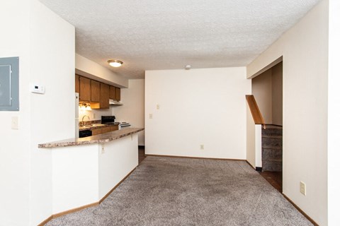 an empty living room and kitchen with a counter top