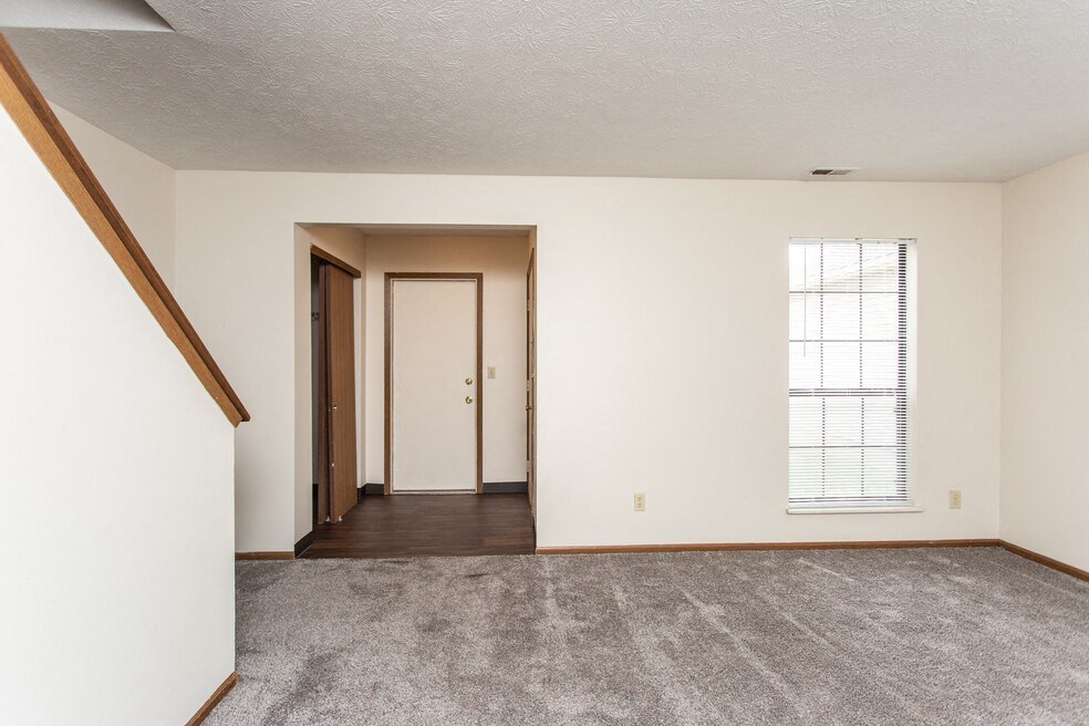 an empty living room with a door to a hallway and a window