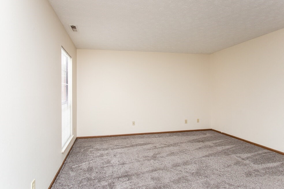 an empty living room with carpet and a window