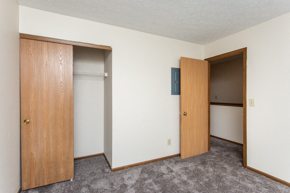 an empty bedroom with two doors and a closet