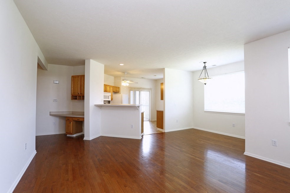 an empty living room and kitchen with wood flooring