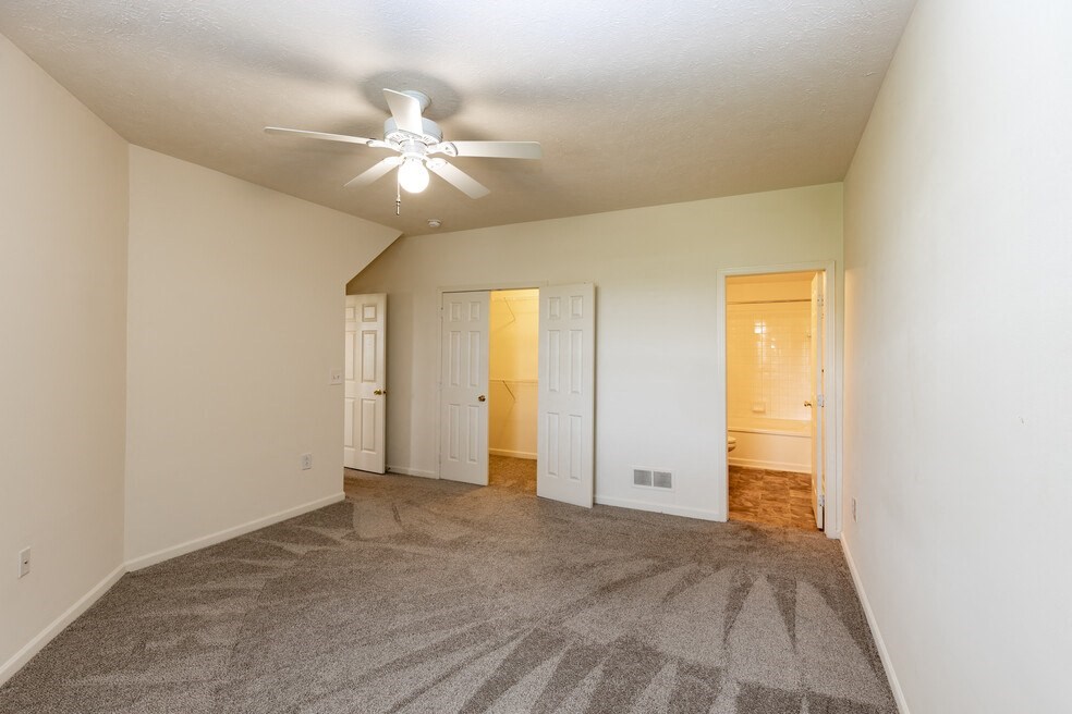 a spacious living room with carpet and a ceiling fan