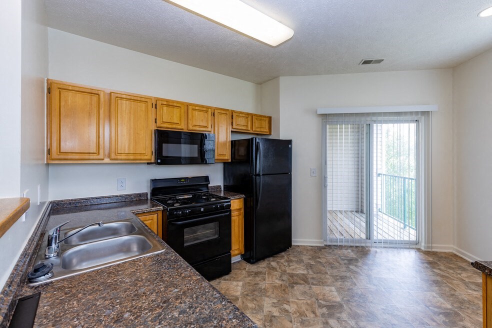 an empty kitchen with black appliances and wooden cabinets