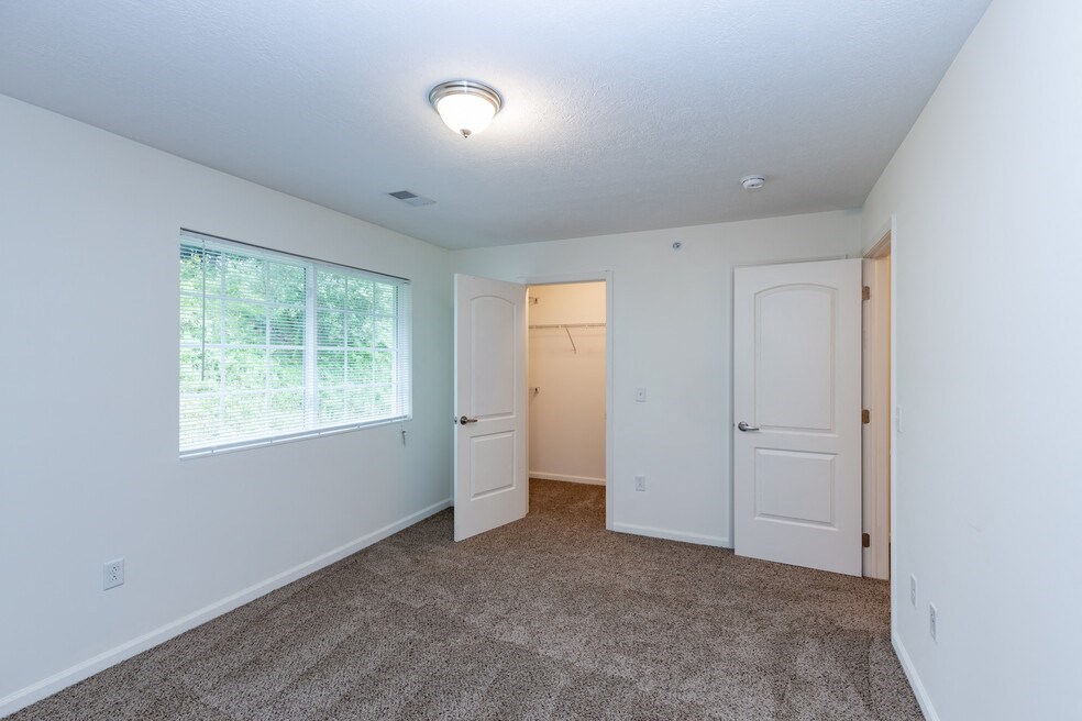 a bedroom with a large window and a door to a closet