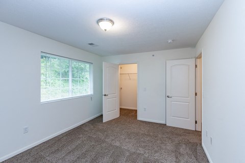 a bedroom with a large window and a door to a closet