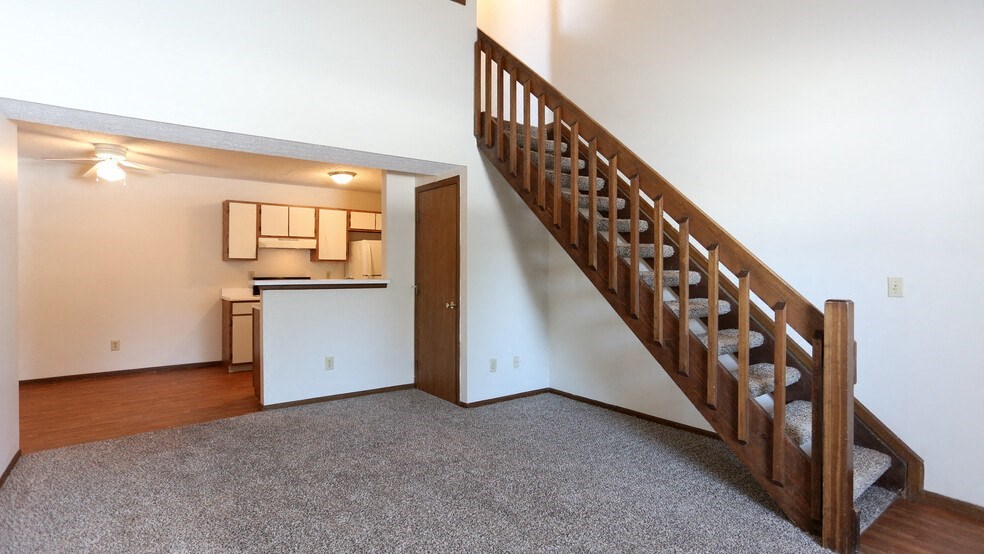 a stairway in a living room with a kitchen in the background