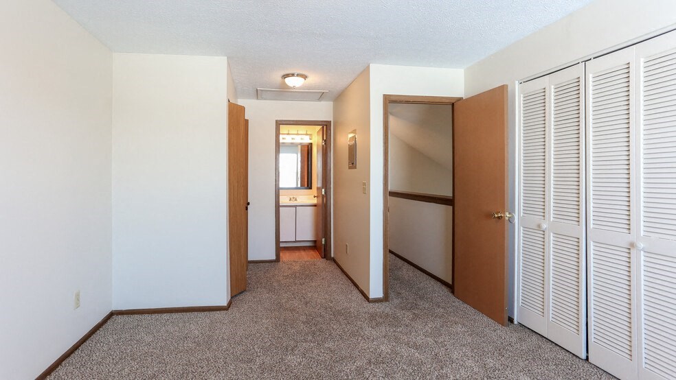 a bedroom with a door to a closet and a bathroom