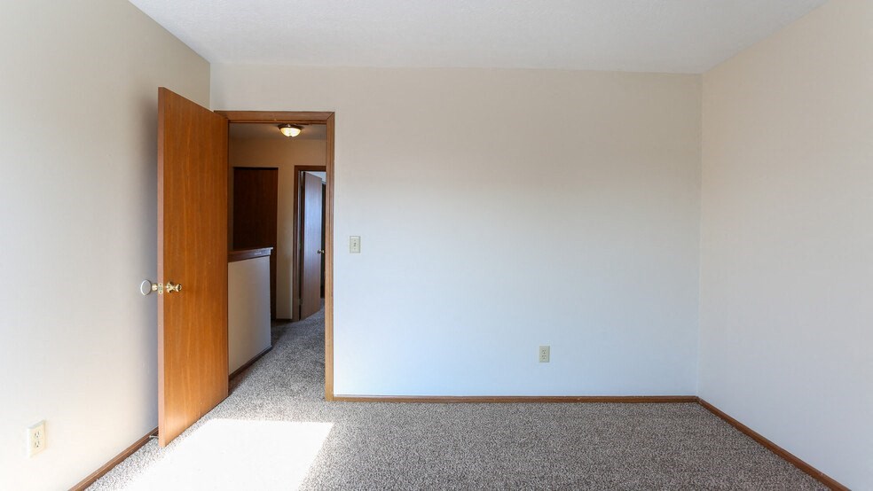 an empty living room with a door to a kitchen