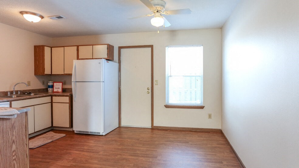 an empty kitchen with a refrigerator and a window