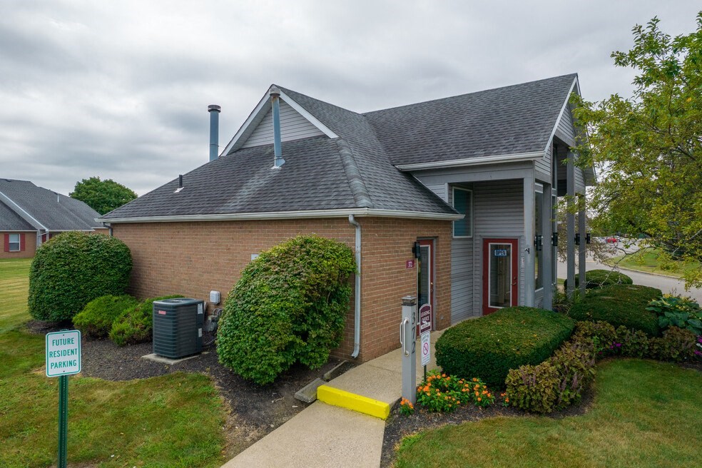 the front of a brick house with a yard and a sidewalk