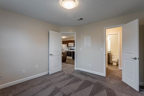 a bedroom with a door open to a bathroom and a closet