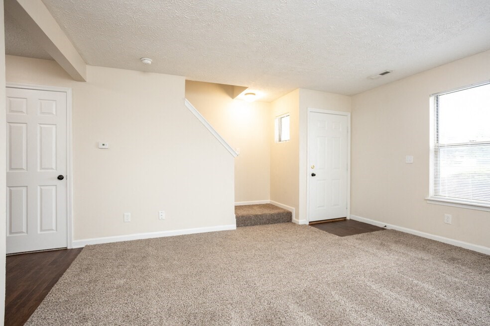 an empty living room with two doors and a window