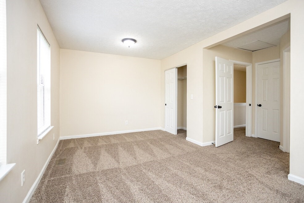 an empty living room with carpet and a door to a closet