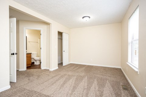 a spacious living room with carpet and a bathroom
