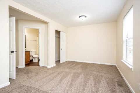 a spacious living room with carpet and a bathroom