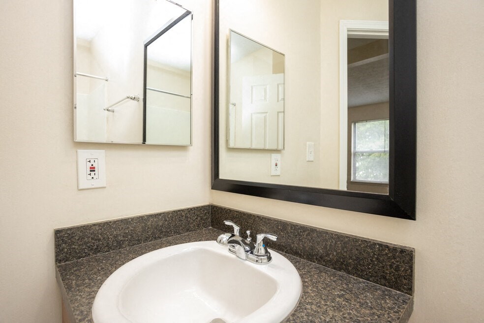 a bathroom with a sink and two mirrors