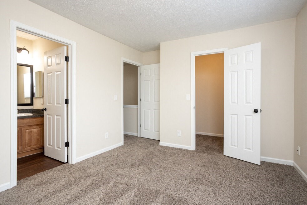 an empty living room with white doors and carpeting