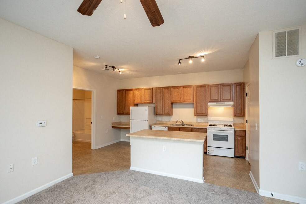 an empty kitchen with white appliances and wooden cabinets