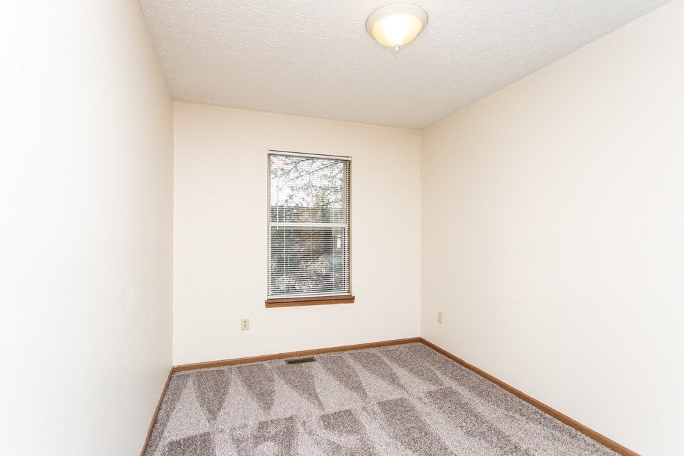an empty room with a window and carpet