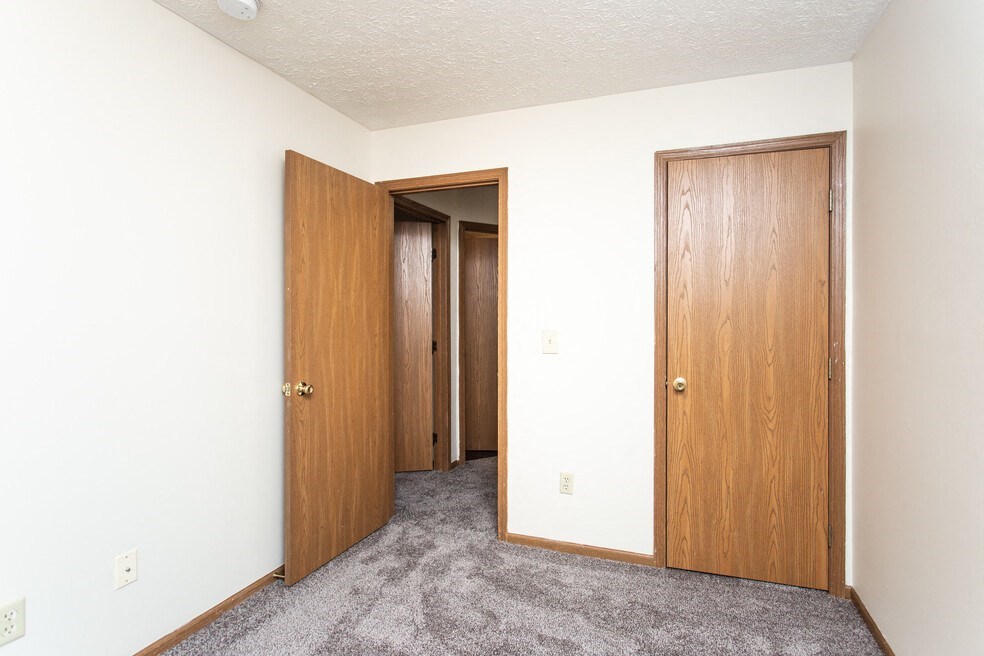 a bedroom with two doors and a carpeted floor and two closets