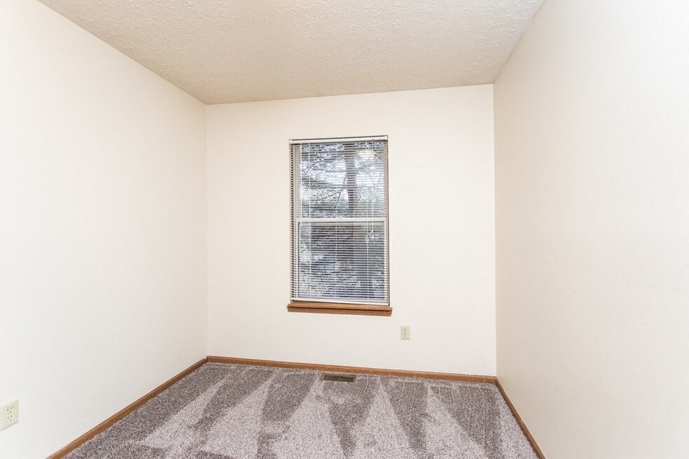an empty room with a window and carpet
