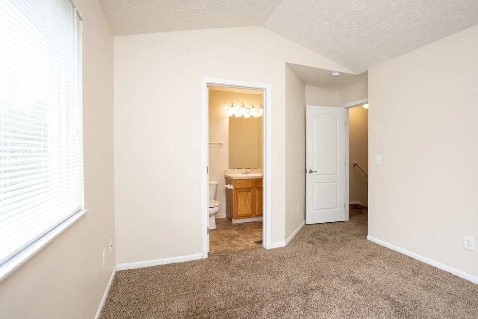 a bedroom with a door to a bathroom and a closet