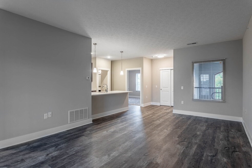 the living room and kitchen of an empty house with wood flooring