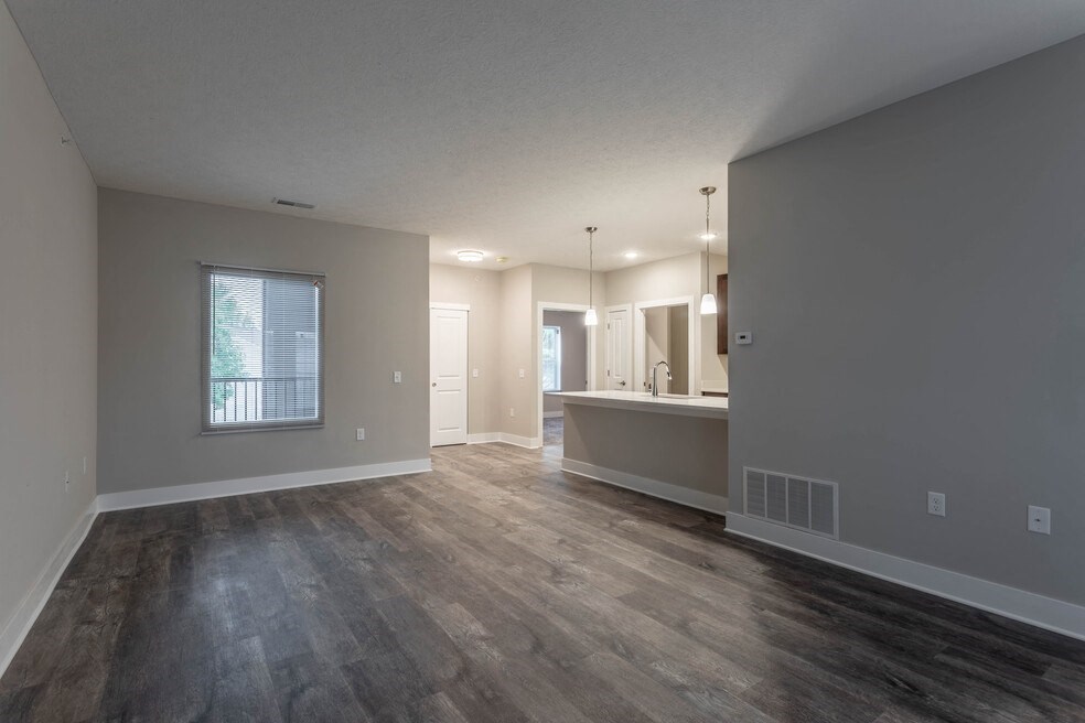 the living room and kitchen of an empty home with wood flooring