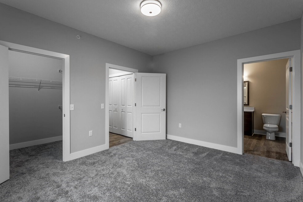 a bedroom with a door to the bathroom and a closet