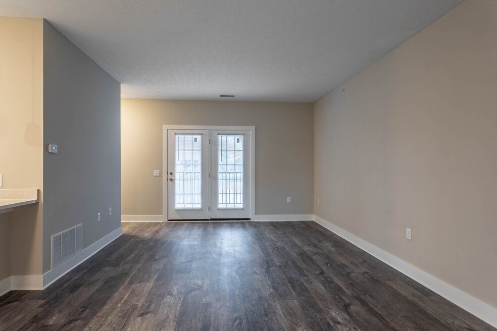 the living room of an empty house with wood floors and a door