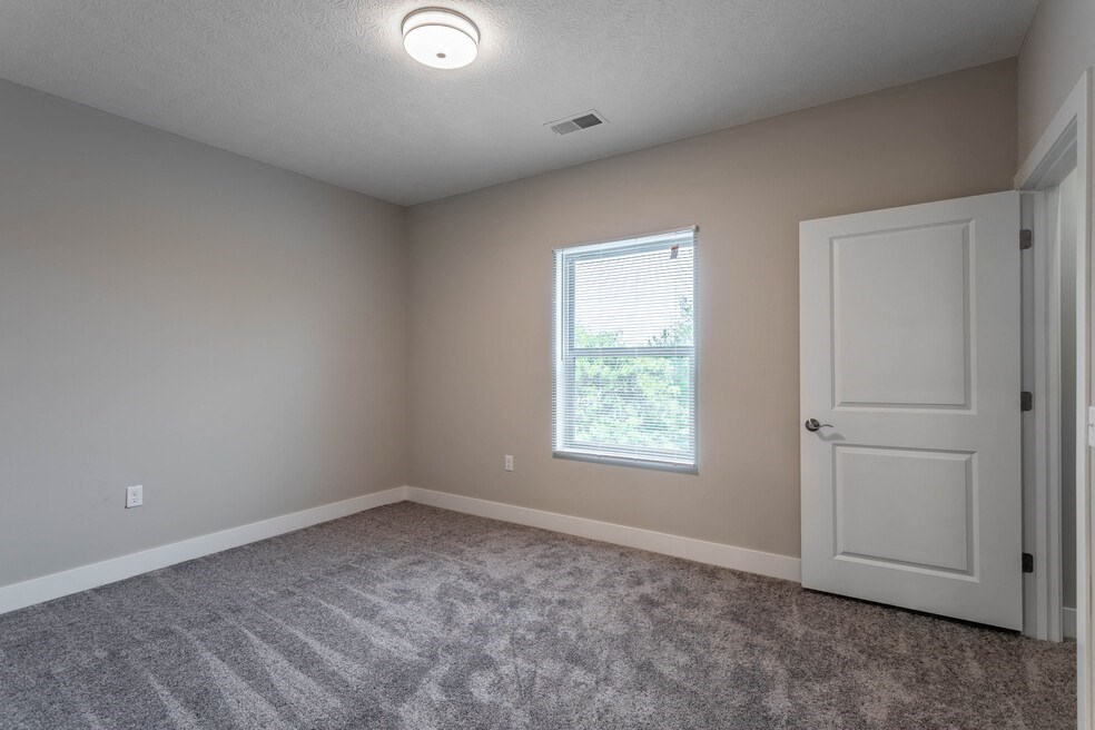an empty living room with a white door and a window