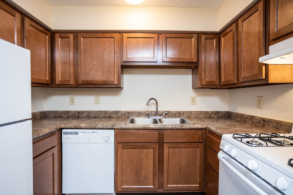 a kitchen with wood cabinets and white appliances and a sink