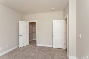 A room with two white doors and carpeted flooring.