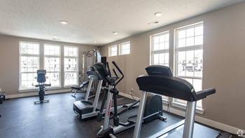 A gym with treadmills, elliptical machines, and a stationary bike.