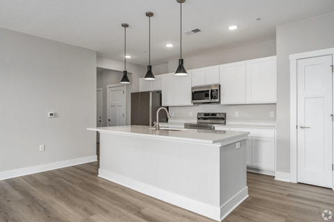A modern kitchen with a white island and pendant lights.