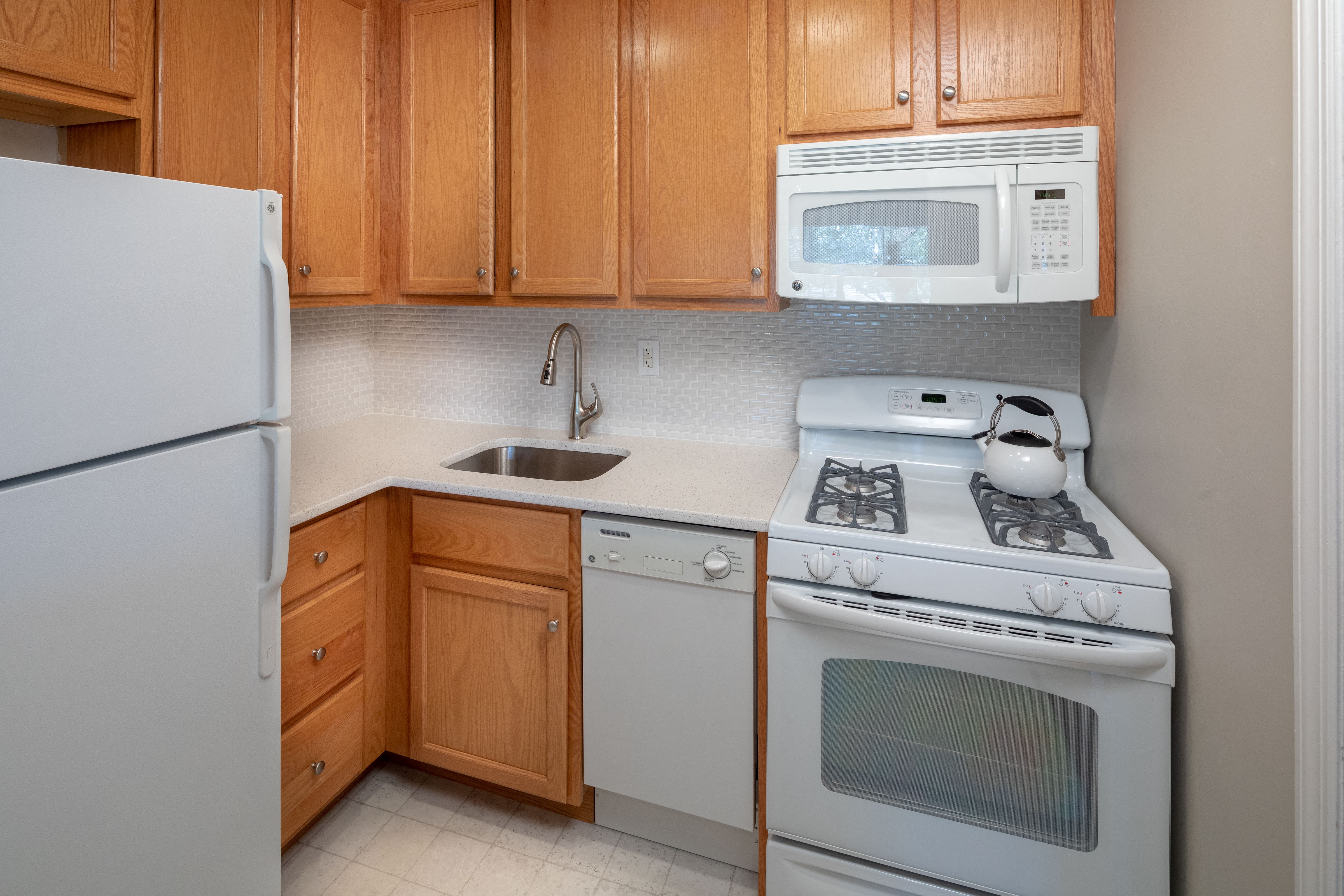 A kitchen with a white refrigerator, white stove, and white microwave.