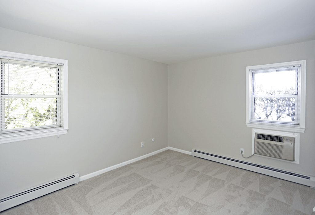 A room with a window and a carpeted floor.