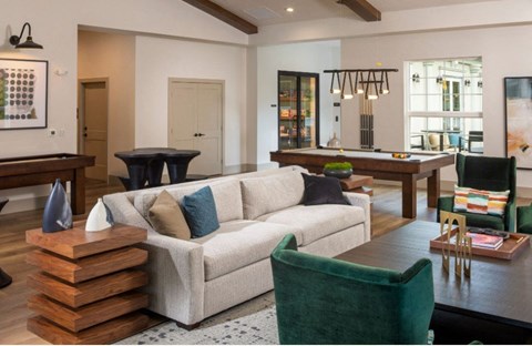 a living room with a couch and chairs and a pool table