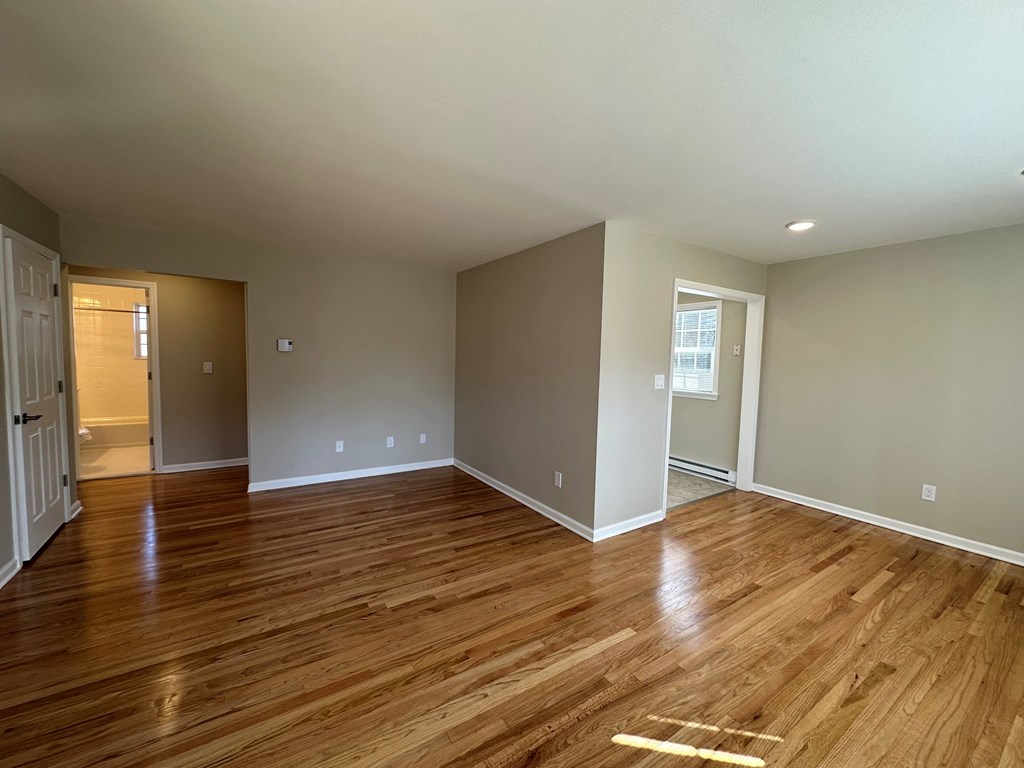 a living room with wood floors and a door to a bathroom