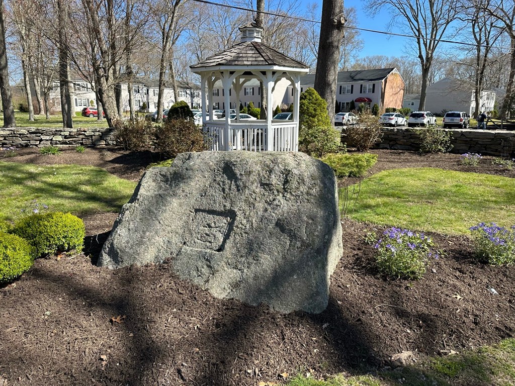 a large rock in a garden with a white gazebo